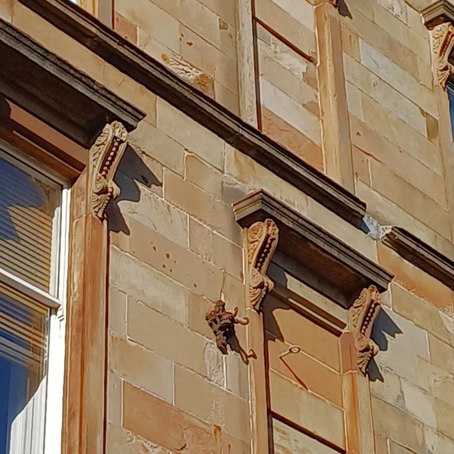 Close-up of carved sandstone window dressings on a Glasgow tenement