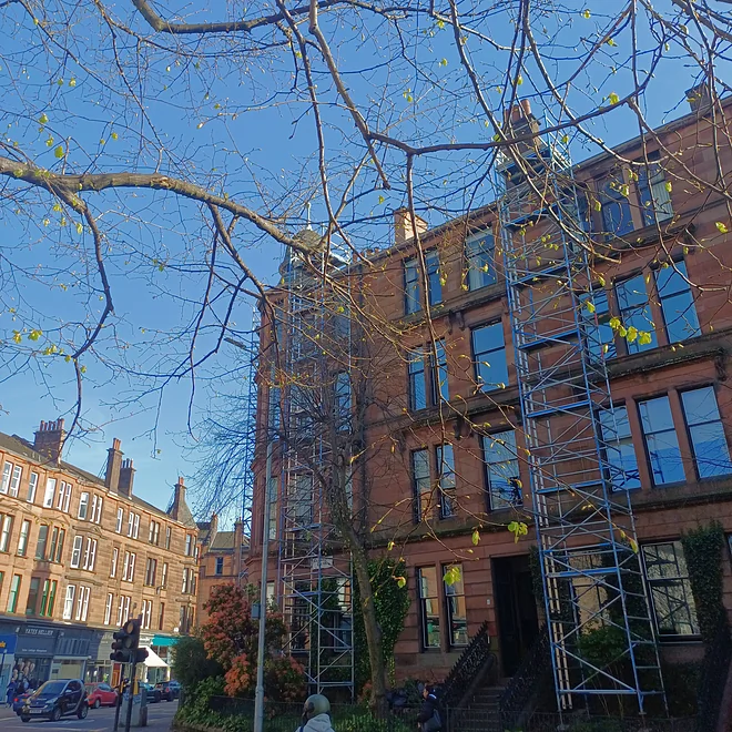 Well-maintained Glasgow tenement street with trees and residents