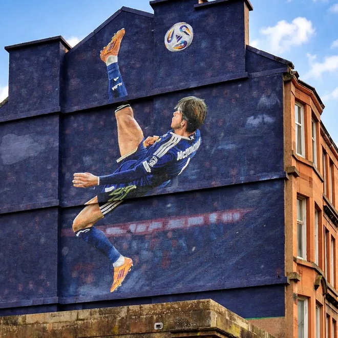 Scott McTominay overhead-kick mural on a Glasgow tenement gable end near Hampden